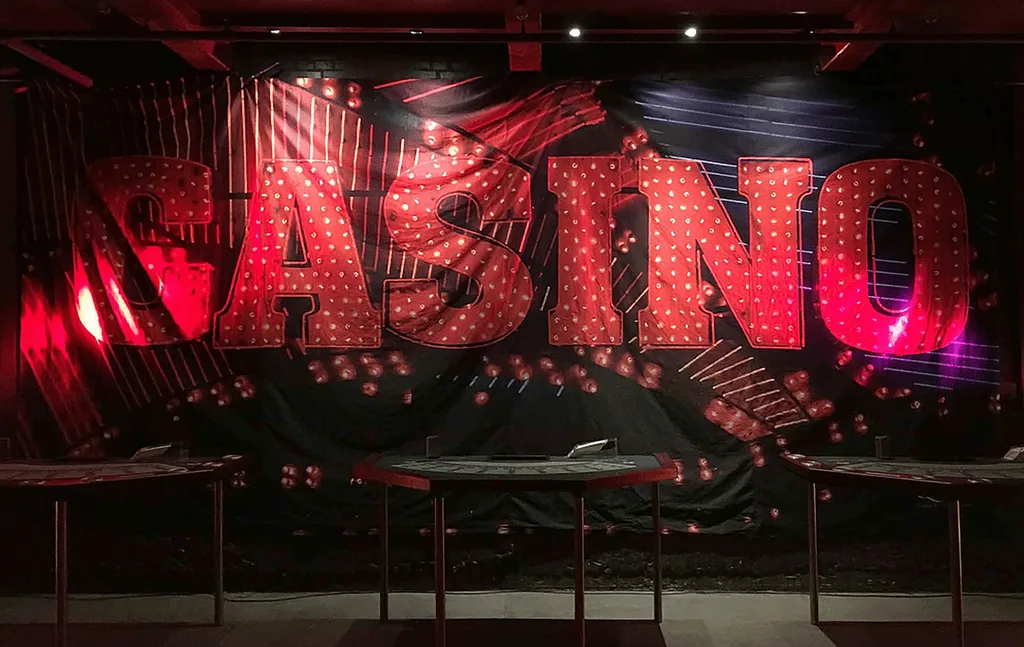 Stort rødt CASINO-skilt med pærer over spillebordene