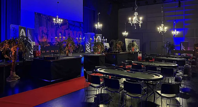 Spilleborde og palmer i en casinosal med blåt lys