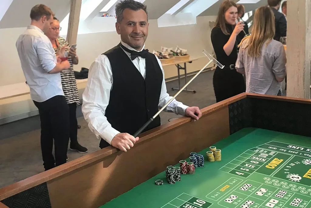Dealer med craps-stok ved craps-bordet med jetoner på filten