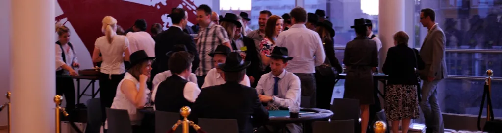 Pokerturnering med gæster i hatte ved bordene i en lys festsal