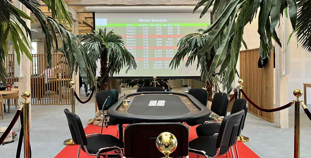Finalebord til pokerturnering med rød løber og blindsskema på skærm